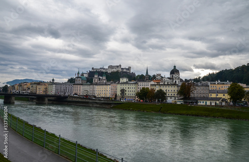 Autumn view with Salzach river, Salzburg Cathedral (Salzburger Dom) and Hohensalzburg Fortress on hill top with cloudy sky at the background.