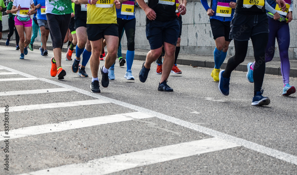 Detail of a group of runners during a city marathon. Legs and sneakers. Muscles under stress. Sport concept