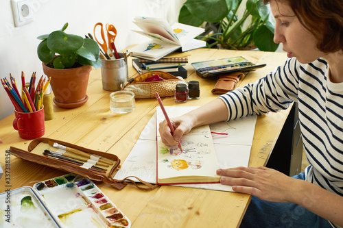 Close-up image of artist drawing in a sketchbook. Female designer working from home. Creative cozy workplace photo
