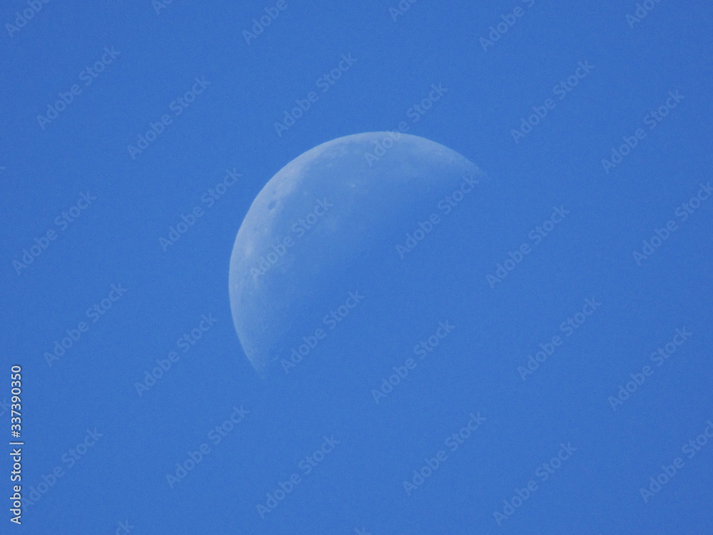 Incomplete white moon in the afternoon on a blue sky Incomplete white moon in the afternoon on a blue sky