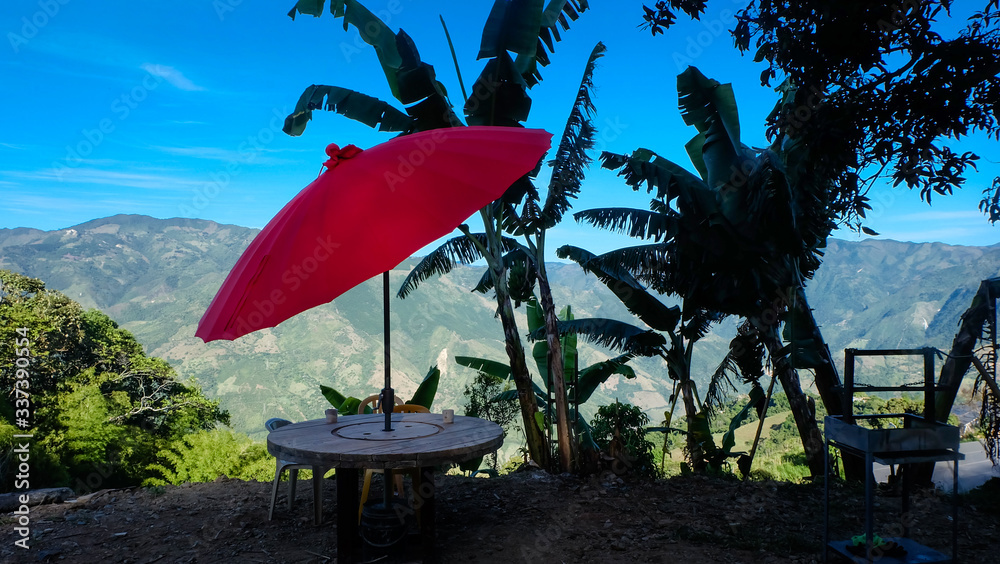 red umbrella next to banana trees overlooking the mountains of Antioquia Colombia