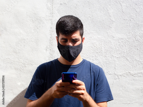 Young man with a black face mask using a mobile