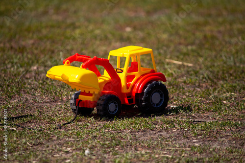 Toy yellow-red tractor on the ground, children's things