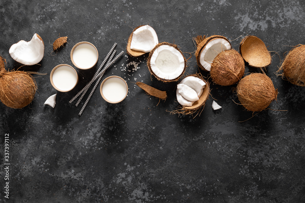 Coconut milk, whole and cracked coconuts on black background, top view Coconut milk, whole and cracked coconuts on black background, top view