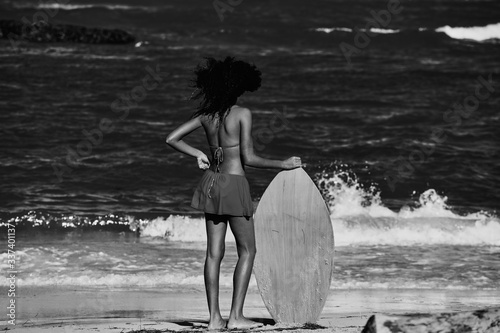 Young curly-haired girl with a Skimboard on the beach. Water sport activity, Atlantic Ocean photo