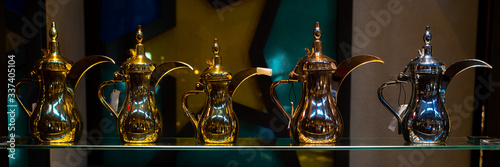 Eastern pitchers stand on a shelf in an Arab shop. Copper glasses, trays, bottles and jars at the brass traders shop.