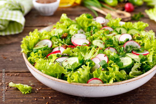 Fresh vegan vegetable salad of radish, cucumbers, lettuce, dill and green onion, healthy vegetarian food