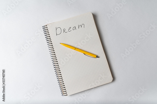 Top view of notepad with inscription Dream and pen. Motivational note. Wish list