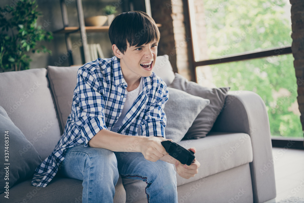 Photo of teenager school boy sit comfy couch stay home quarantine time hold joystick playing video game addicted gamer excited mood trying hard living room indoors Photo of teenager school boy sit comfy couch stay home quarantine time hold joystick playing video game addicted gamer excited mood trying hard living room indoors