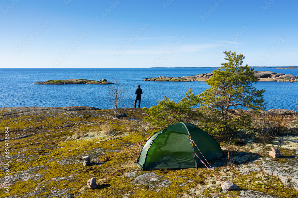A man with a tent on the shore of the Baltic sea.