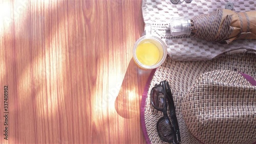 Ready to travel. Top view beach background of essential modern summer women accessories in wooden table. Sunglasses, umbrella, Straw hat, Beach bag and a glass of lime juice. Room for text on left.