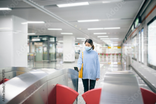 That young Asian woman wearing a surgical mask using smart phone to pay in the subway station.
