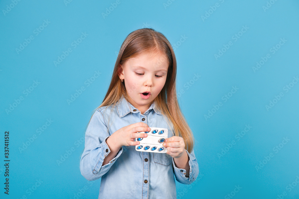 Little girl with tablets in her hands on blue background Little girl with tablets in her hands on blue background