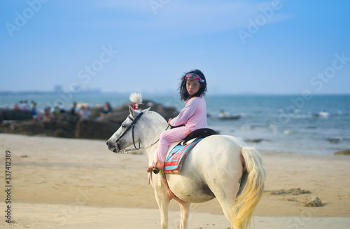 girl in swimming suit ride horse on beach front in summer holiday