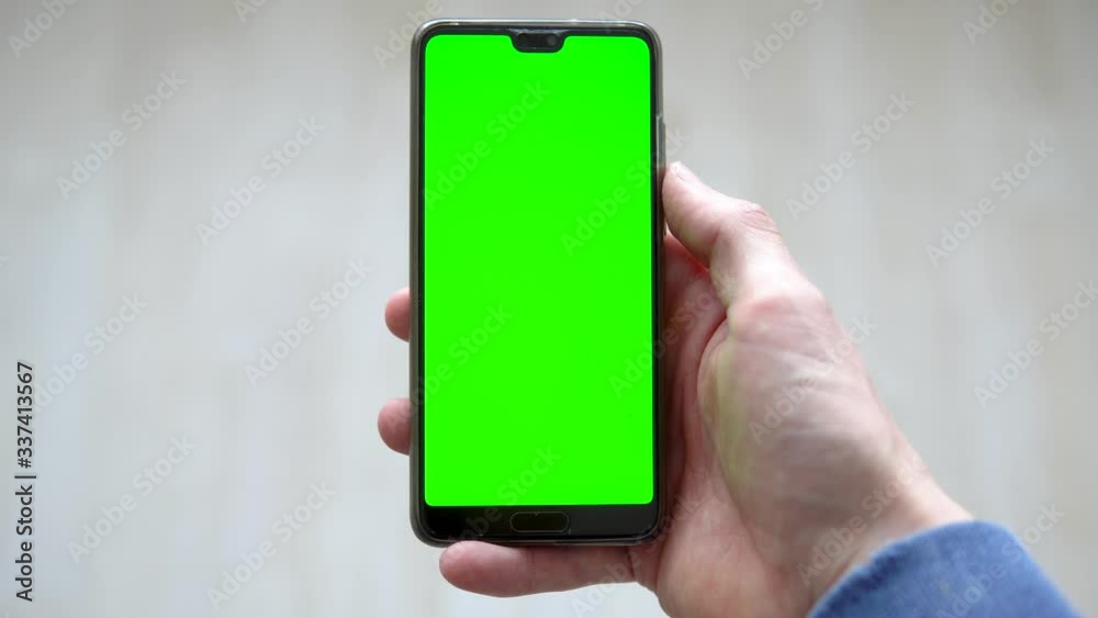 Top view of white male holding smartphone. Editable greenscreen on mobile device. Top view of white male holding smartphone. Editable greenscreen on mobile device.
