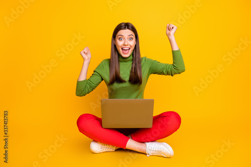 Photo of beautiful lady sit floor hold notebook read online table with examination results celebrate best grade mark wear green sweater red trousers isolated yellow color background © deagreez