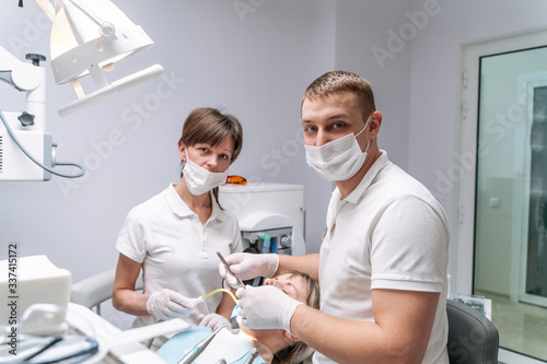 Two dentists examine the patient s teeth for the further treatment. Modern stomatology cabinet.