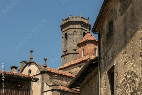 View of the tiled roofs of ancient stone and brick buildings with towers and domes of various shapes and finishes against a blue sky
