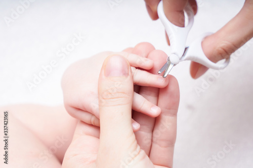 mother trim the baby nails on the handles with baby scissors