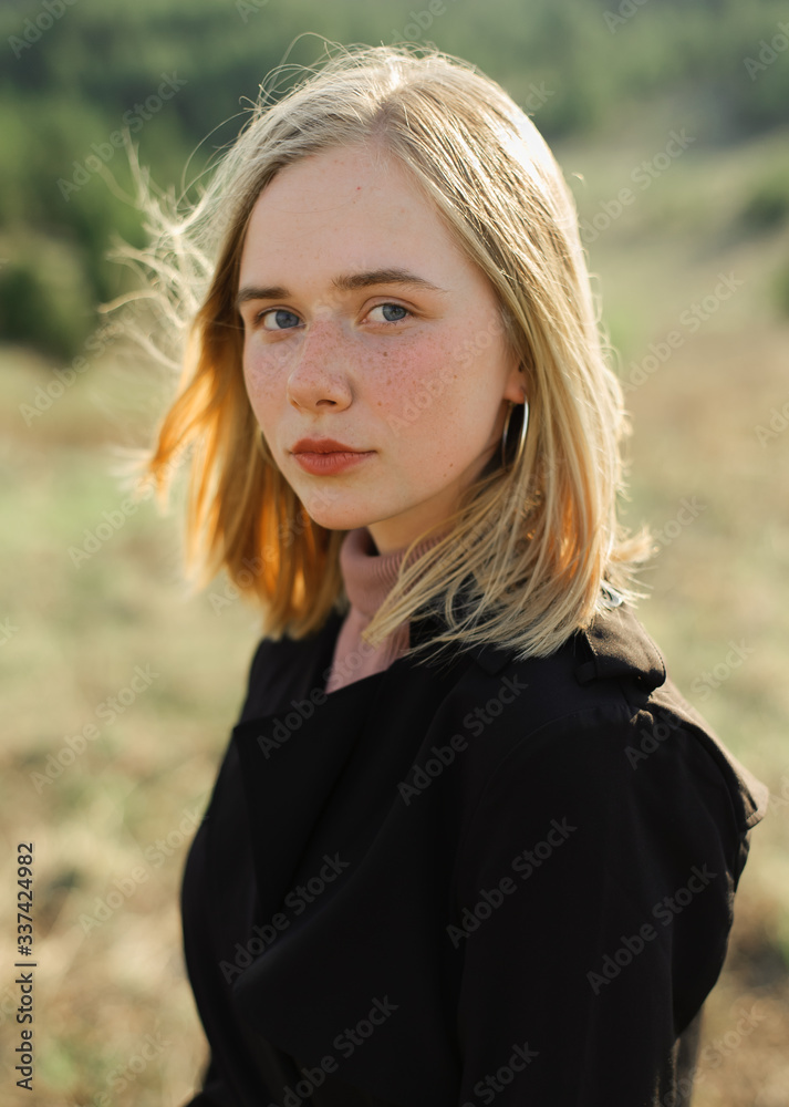 Closeup portrait of a beautiful blonde girl with freckles. Attractive young woman at sunset outdoors. Closeup portrait of a beautiful blonde girl with freckles. Attractive young woman at sunset outdoors.