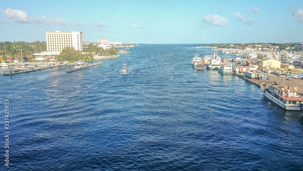 Local harbor in Atlantic ocean, Bahamas.  Boats on turquoise ocean water on blue sky with white clouds background.