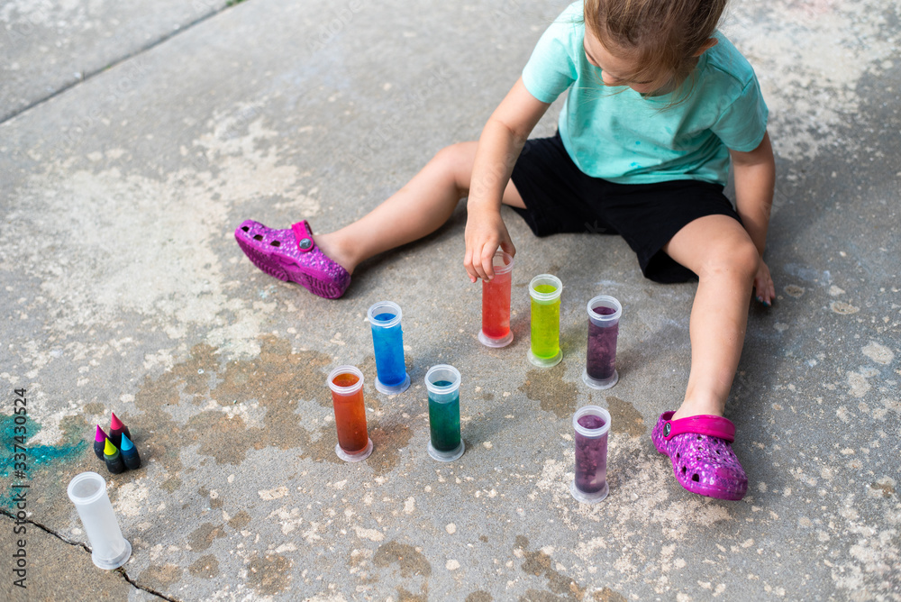 Fototapeta premium Toddler art project, playing outside with food coloring, test tubes, fun activity for learning in early childhood 