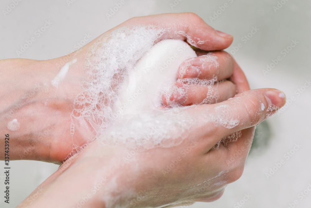 Woman uses soap and washes her hands under a faucet. Hygiene and hand cleaning. Prevention and control of coronavirus.