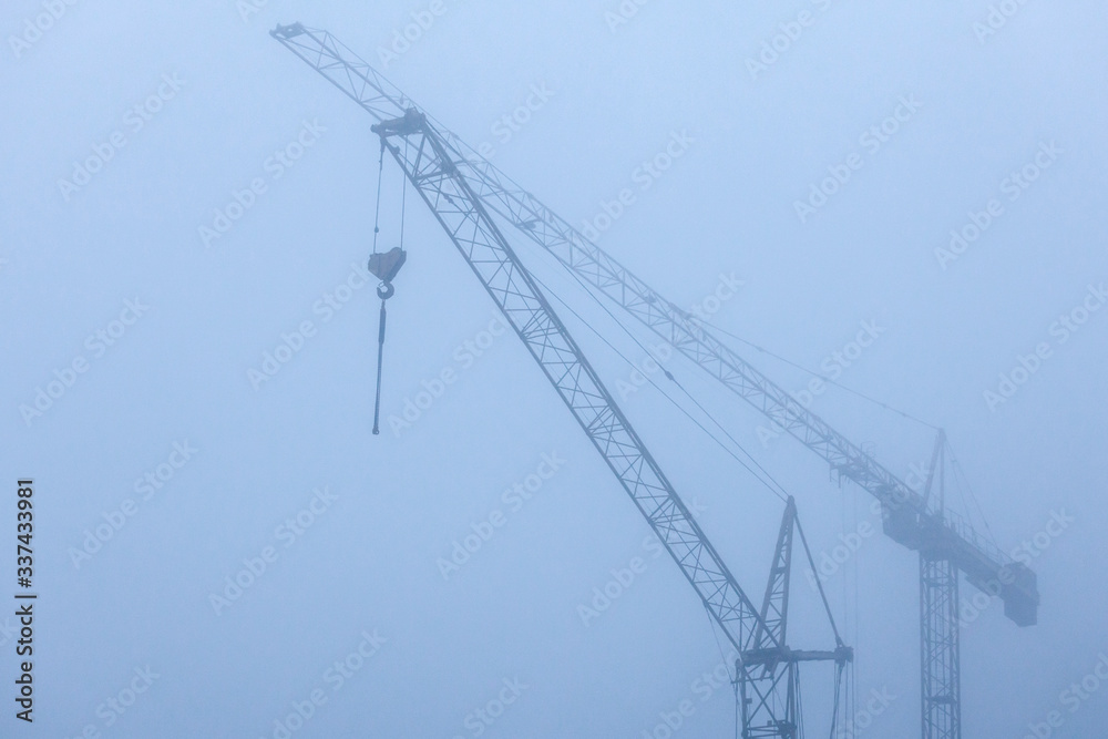 view of construction cranes in the fog