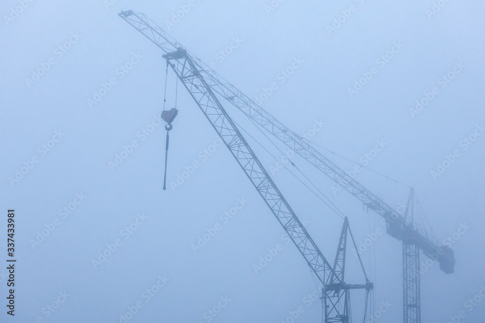 view of construction cranes in the fog view of construction cranes in the fog