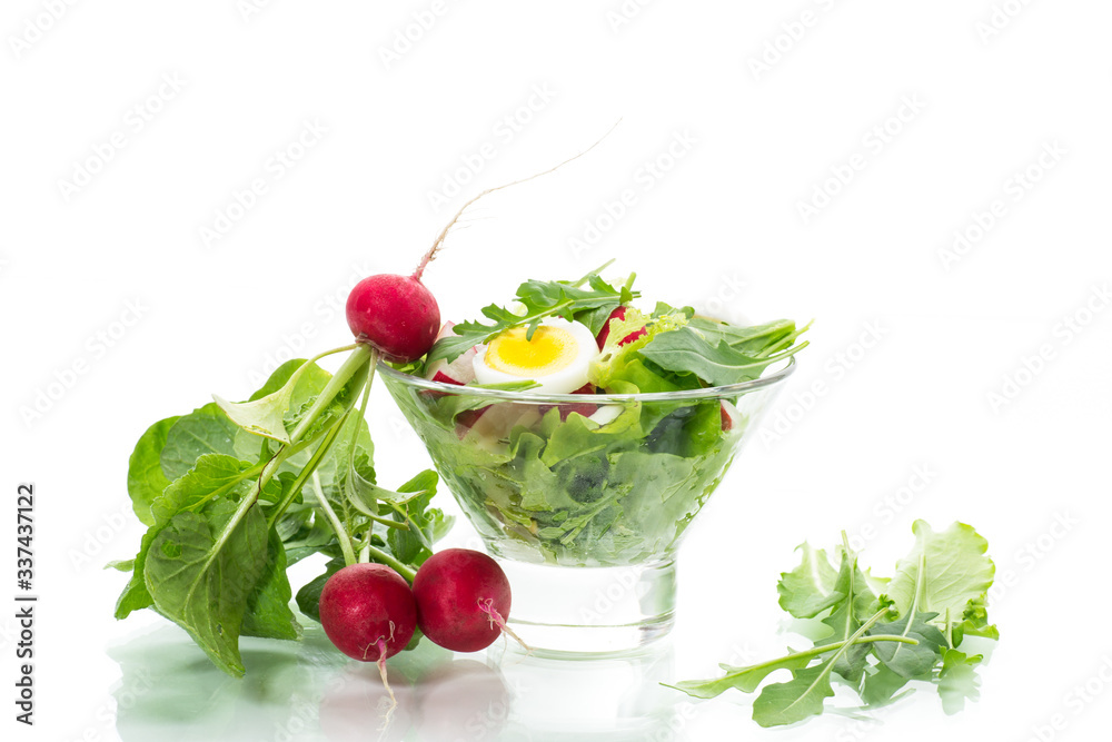 spring salad with arugula, boiled eggs, fresh radish, salad leaves in a glass bowl