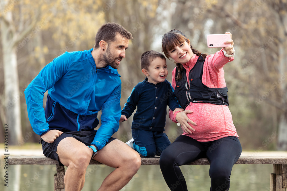 Happy young family taking a selfie with the smartphone while enjoying the time together outdoor. Happy young family taking a selfie with the smartphone while enjoying the time together outdoor.