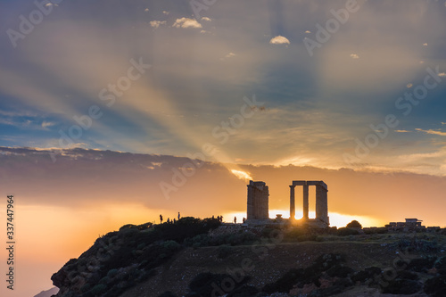 People visiting the famous ancient temple of Poseidon in Cape Sounio near Athens Greece during sunset with beautiful sun rays