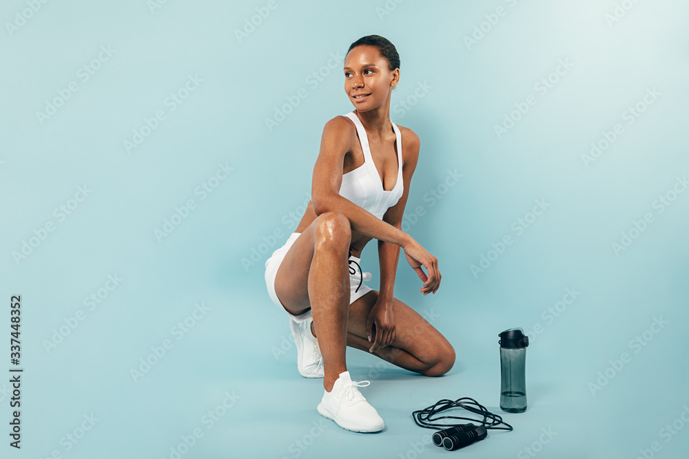 Fototapeta premium Smiling woman resting after training in studio looking away 