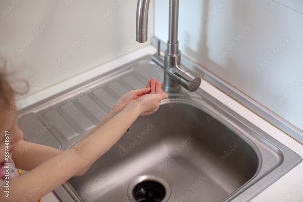 Little girl washing her hand. With soap under the tap. Kitchen interior. Little girl washing her hand. With soap under the tap. Kitchen interior.