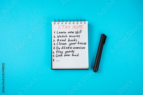 Notepad with stay home check list on covid 19 quarantine. Stay home, stay safe. Read books, play games, watch movies, learn new skill, clean your house, do fitness, cook new meal. 