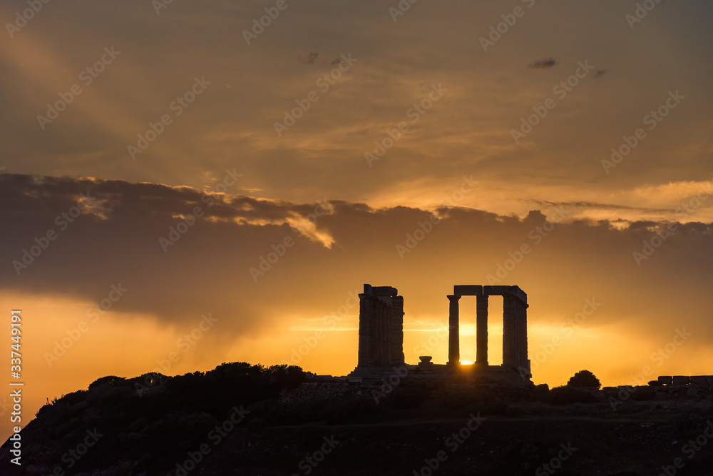 Obraz premium The silhouette of the famous ancient temple of Poseidon in Cape Sounio near Athens Greece during sunset with beautiful sun rays and warm orange light