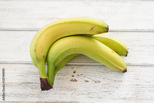 Bunch of green bananas on white wooden background. Fruit close-up photo