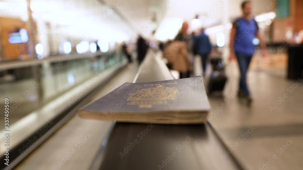 Fixed selective focus shot of a Canadian passport on moving walkway or sidewalk handrail in the airport with blurred passengers people the background.