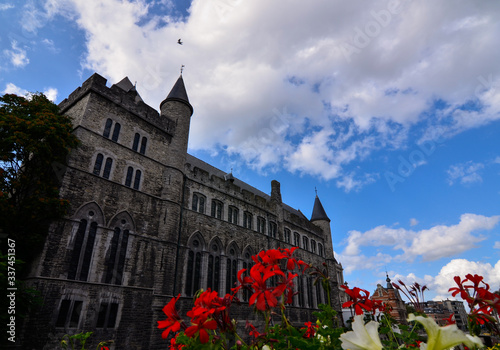 Ghent,Belgium,August 2019.Geraard de Duivelstraat Castle.The main facade overlooks the water: it is an example of the medieval buildings of the city.Blue sky with white clouds.Planters along the canal photo