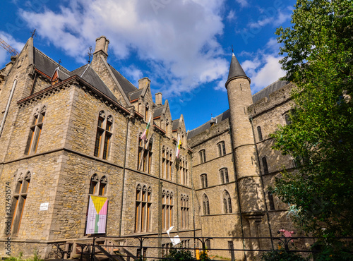 Ghent,Belgium,August 2019.The castle of Geraard de Duivelstraat. View of the internal side,opposite the canal. The elegant tower with the conical roof stands out against the blue sky with white clouds photo