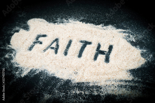 Top view of Faith text written on sand