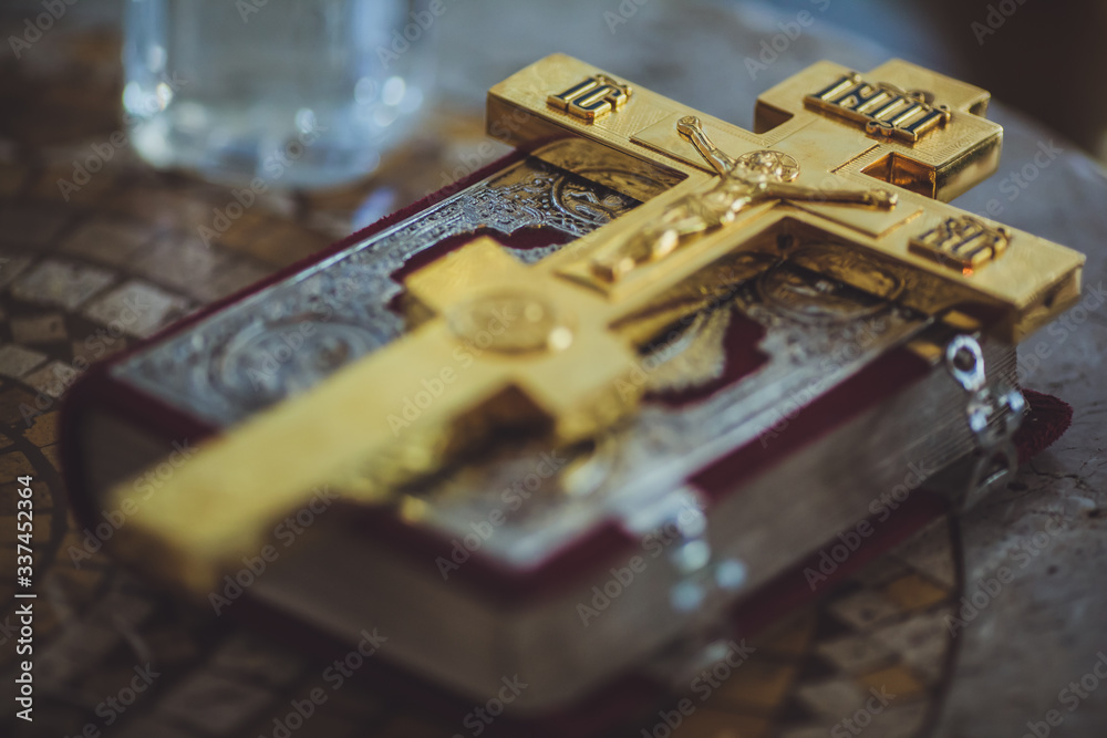 A large gold Orthodox Christian cross is placed on the book. A large gold Orthodox Christian cross is placed on the book.