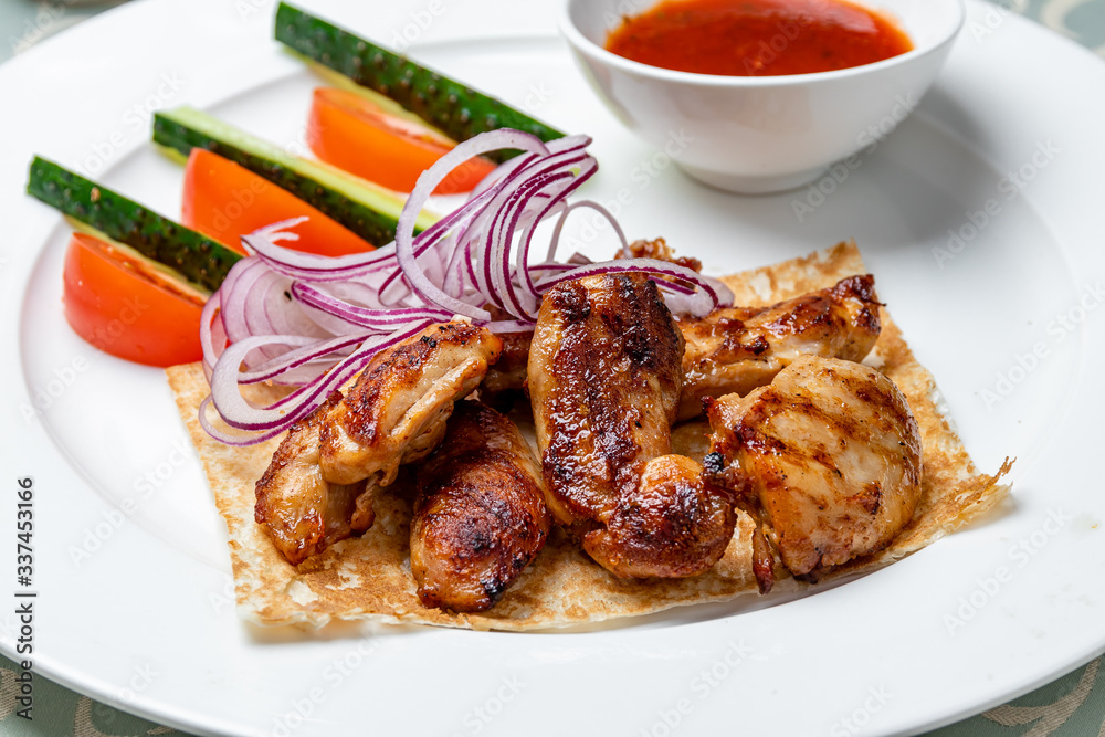 chicken kebab on a white plate with tomato sause