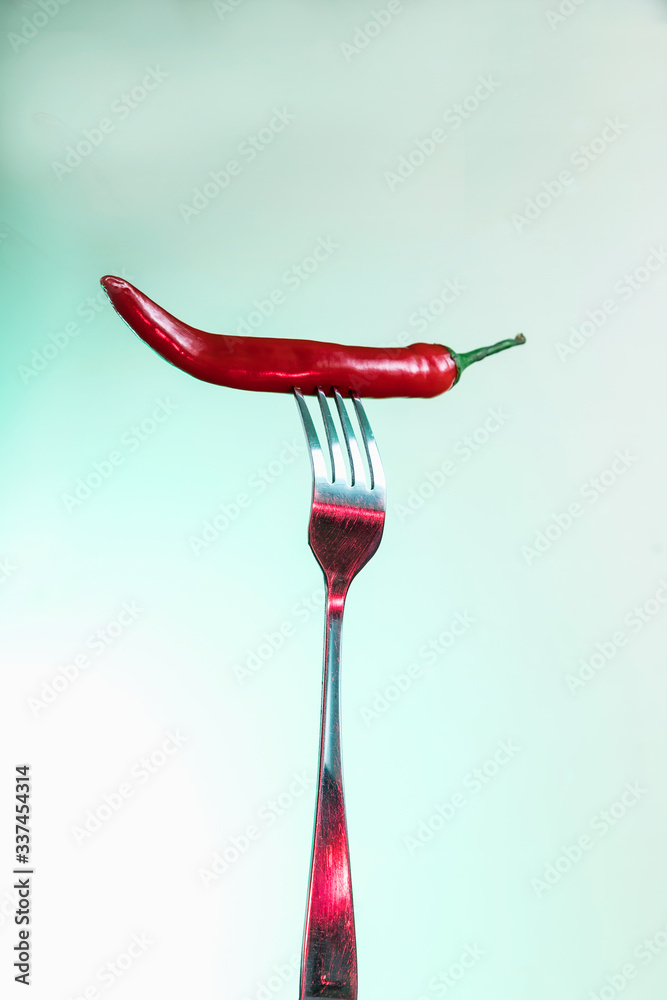 Red chili pepper on a fork. Sharp fork and about hot pepper. Red chili pepper on a fork. Sharp fork and about hot pepper.