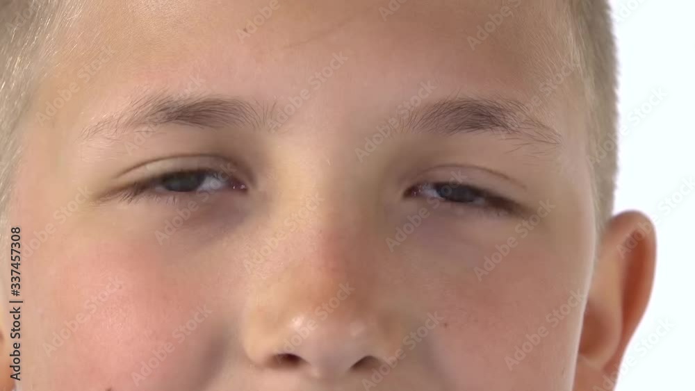 Blond little boy with light eyes looks directly at camera in surprise on white background. Close up of eyes. Slow motion Blond little boy with light eyes looks directly at camera in surprise on white background. Close up of eyes. Slow motion