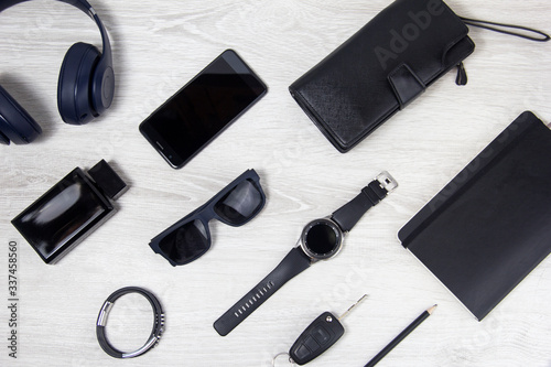 Background men's accessories lie on a wooden background. Black glasses, watch, notebook, wallet are on a light background. Objects close-up, top view