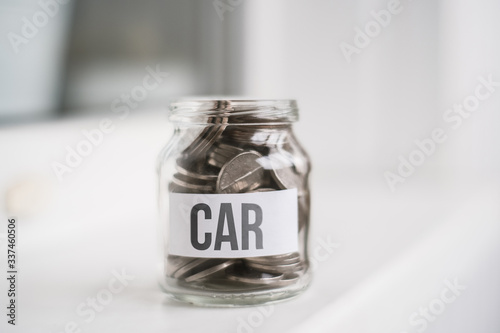 The concept of accumulating money for a car - a glass jar with coins.
