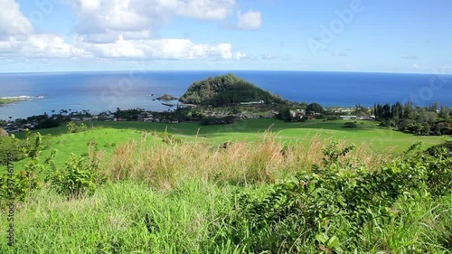 Ka'uiki Head at Hana Bay on Maui as seen from the top of the hill above Hana with cattle pastures on the slopes and blue ocean, blue sky and white clouds in the background on a sunny Hawaii day. photo