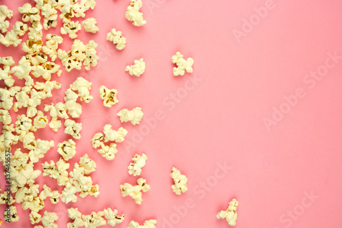 popcorn sprinkled on a pink background, place for text, concept of relaxing and spending free time, watching movies © Victoriia