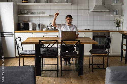 Young freelancer have a great idea working from home. Excited glad young freelancer catch an idea. Euphoric winner happy man using a laptop in a desk at home. Successful bearded man.